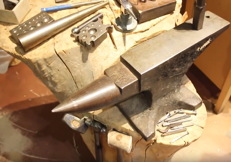 A variety of our makers' tools is shown here—a hand forged anvil and numerous mallets and stamps rest on an old cottonwood stump.