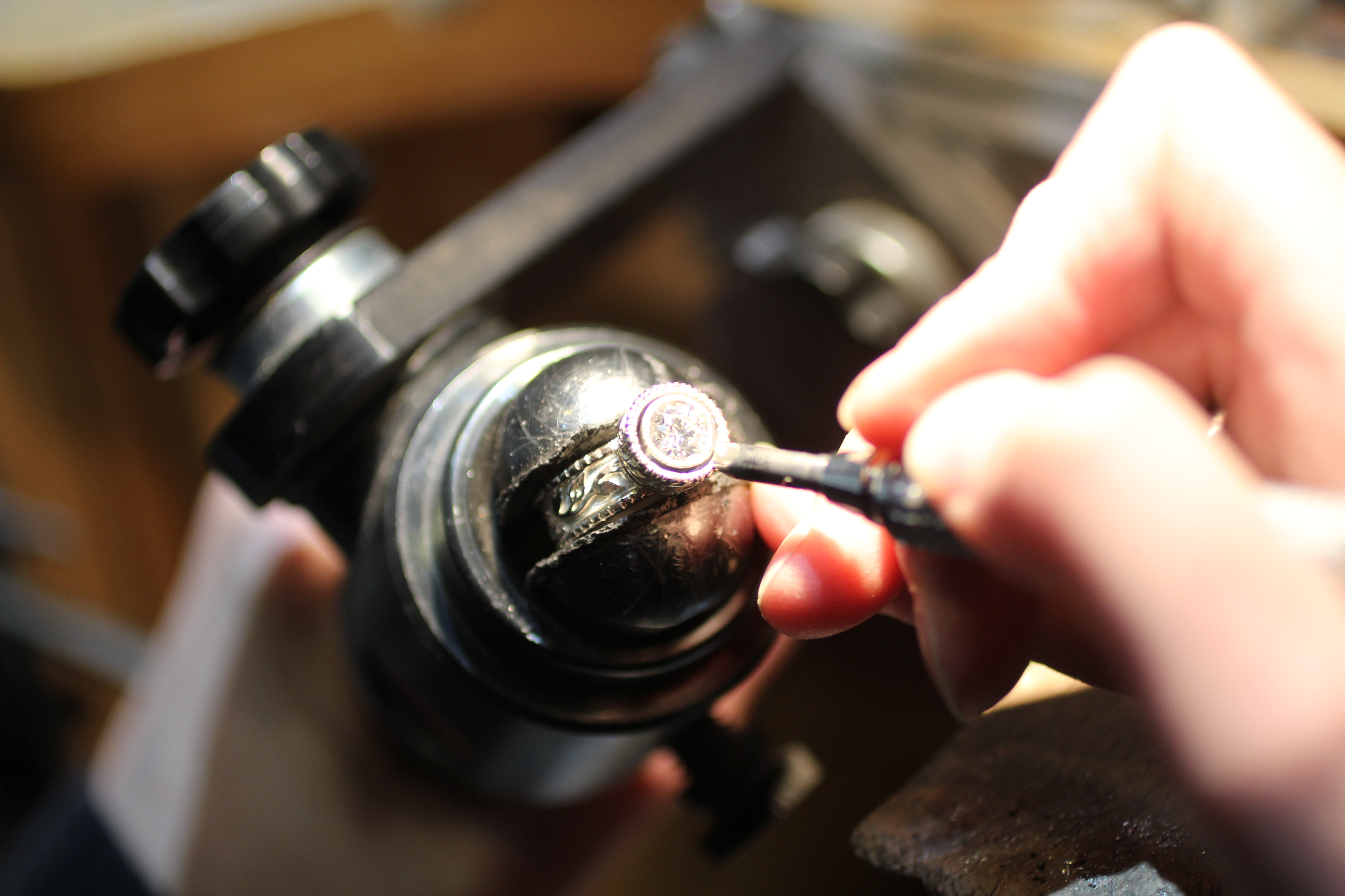 Here, one of our jewelers is shown setting a diamond into a custom engagement ring that uses our Flores motif.